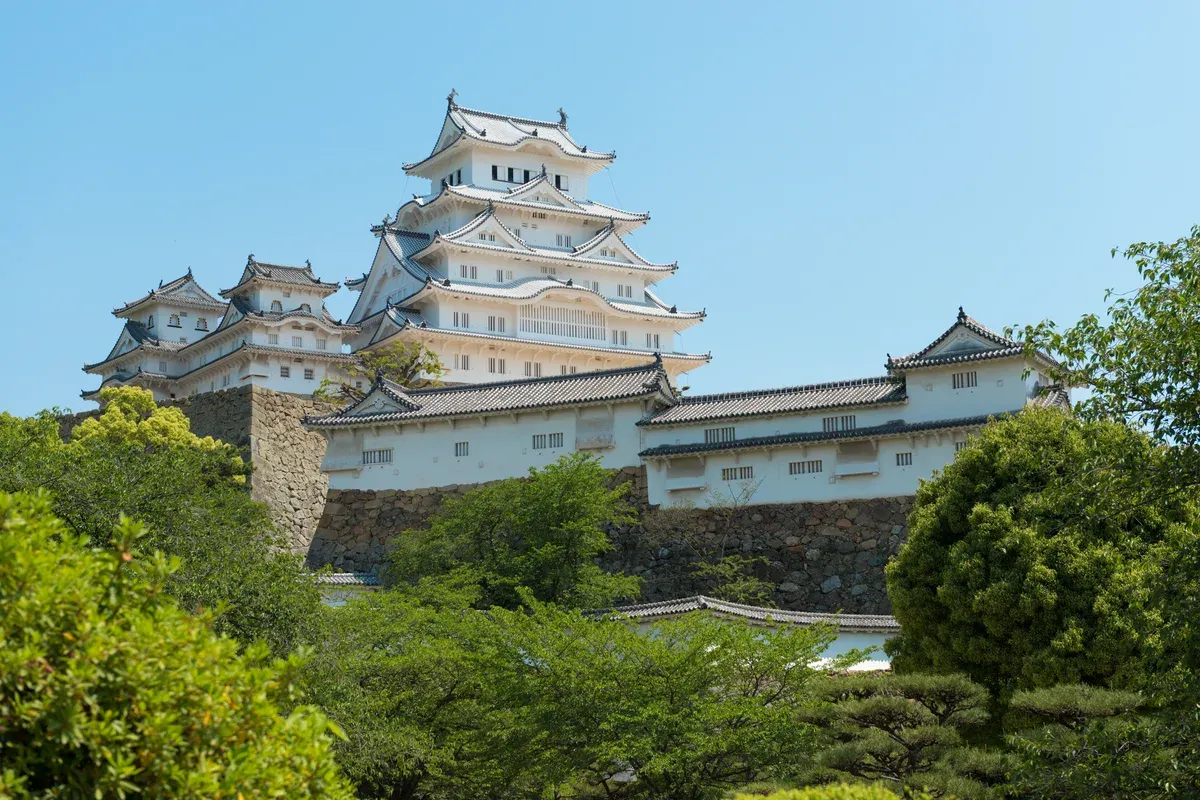 Himeji Castle keep seen across greenery on a day trip from Kyoto